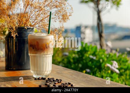 Kaffee mit Milch auf Holztisch im Freien mit Garten backgound in sonnigen Nachmittag Stockfoto
