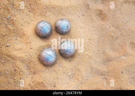 Alte rostige Boccia-Kugeln liegen auf dem Sand. Stockfoto