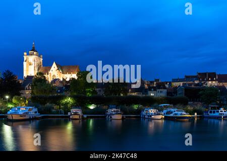 Dole, Frankreich - 14. September 2022: Nachtansicht der beleuchteten katholischen Kirche Notre Dame in Dole mit Hausbooten auf dem Doubs River in der Stirn Stockfoto