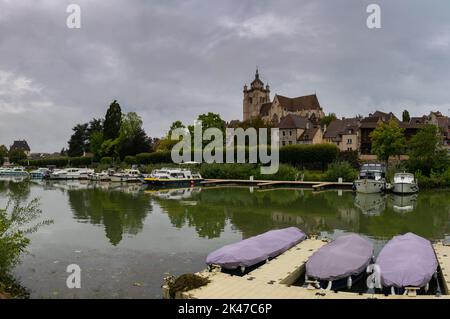 Dole, Frankreich - 14. September 2022: Blick auf den Doubs-Fluss in Dole mit der Kirche auf dem Hügel und Hausbooten, die am Flussufer festgemacht sind Stockfoto