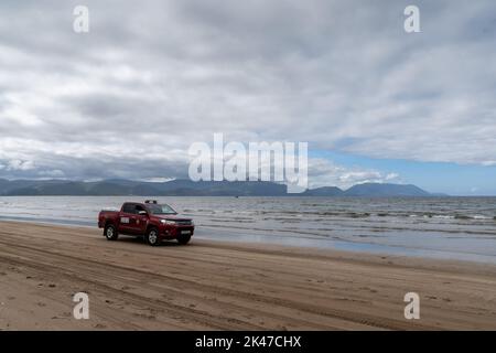 Inch Strand, Irland - 5. August 2022: Red Lifeguard Pick-up Truck fährt am Strand von Inch Strand im Westen Irlands Stockfoto