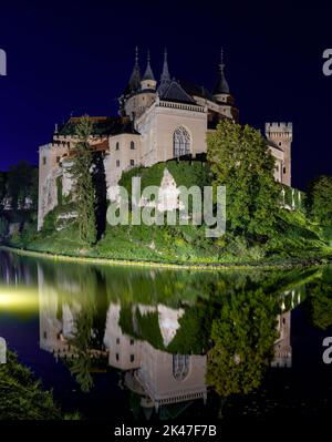 Bojnice, Slowakei - 26. September 2022: Blick auf das Schloss Bojnice mit Spiegelungen im Wasser in der Nacht Stockfoto