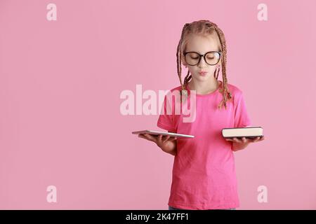 Bücher Vs Gadgets Konzept. Verwirrt Schulmädchen in Brille hält digitale Tablette und Papier Handbuch Buch, Vergleich sie, unsicher teen Wahl, Panora Stockfoto