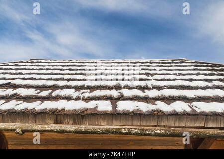 Verfaultes Holzdach mit Schnee bedeckt. Alp Dorf in Slowenien Stockfoto