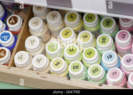 Mehrfarbige Acrylfarben in nummerierten Dosen auf Lagerregalen Stockfoto
