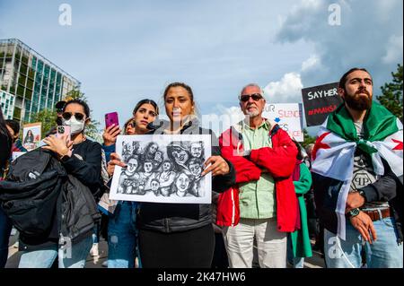 Den Haag, Niederlande. 30. September 2022. Eine iranische Frau zeigt eine Illustration einer Frau, die während der Demonstration keinen Hijab trägt. Das iranische Volk versammelte sich vor dem Internationalen Strafgerichtshof in Den Haag, um die Stimme des iranischen Volkes zu erheben und Gerechtigkeit für die systematischen Verbrechen und Gewalt zu fordern, die von den Behörden des islamischen Regimes gegen die Iraner begangen wurden. Die Proteste im Iran und in der ganzen Welt haben sich in dieser Woche verstärkt wegen des Todes der 22-jährigen Mahsa Amini in Polizeigewahrsam, nachdem sie verhaftet wurde, weil sie angeblich ihr Kopftuch zu locker getragen hatte. Stockfoto