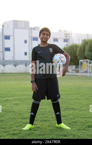 Fußballspieler für junge Kinder, der mit dem offiziellen FIFA Qatar Match Ball auf der Straße spielt. Al-Rhila Stockfoto