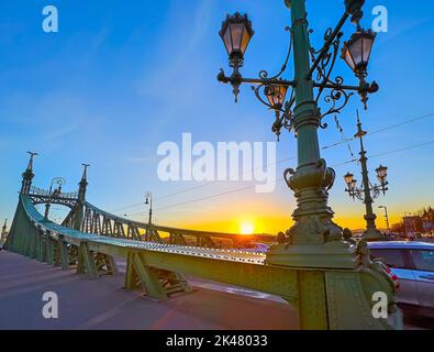 Der goldene Sonnenaufgang hinter den grünen Bauten der berühmten Freiheitsbrücke, Budapest, Ungarn Stockfoto