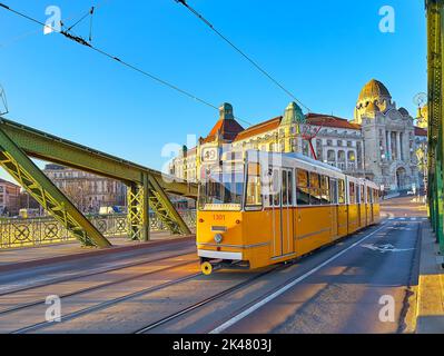 Die alte gelbe Straßenbahn, die auf der grünen historischen Freiheitsbrücke fährt, verbindet Buda und Pest Viertel von Budapest, Ungarn Stockfoto