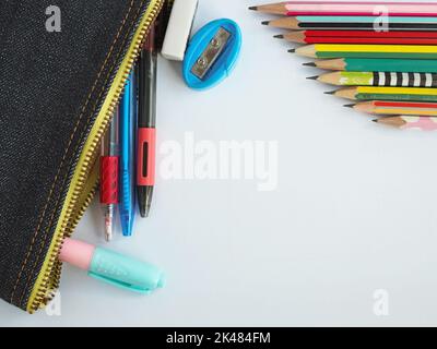 Die Draufsicht auf Schreibwaren in Schultaschen und Bleistiften auf weißem Hintergrund. Stockfoto