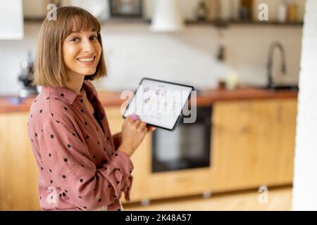 Frau steuert Heimgeräte mit einem digitalen Tablet zu Hause Stockfoto