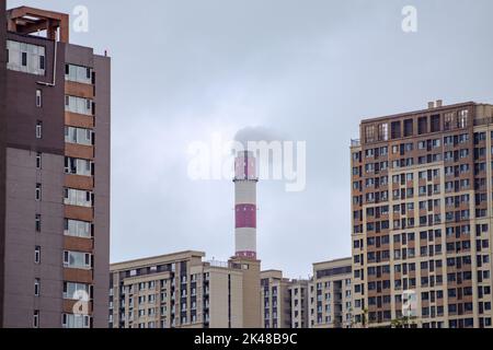 Gebäude in der Stadt. Rauch kommt aus Kaminen und berührt den bewölkten Himmel im Hintergrund. Stockfoto