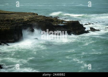 Langzeitbelichtung von Wellen, die am Hangpunkt, dem südlichsten Punkt von South Island, Neuseeland, auf die Felsen spritzen. Stockfoto