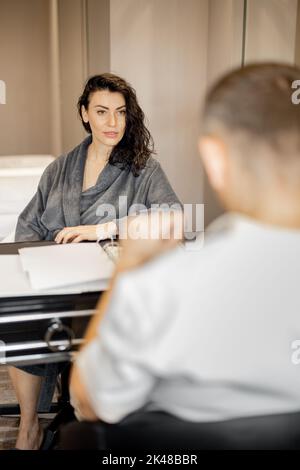 Frau im Bademantel nach Vereinbarung mit Seniortherapeut Stockfoto