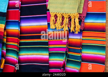 Bunte mexikanische Serape Streifen Decken auf dem Straßenmarkt. Traditionelle handgemachte Souvenirs aus Mexiko zum Verkauf Stockfoto
