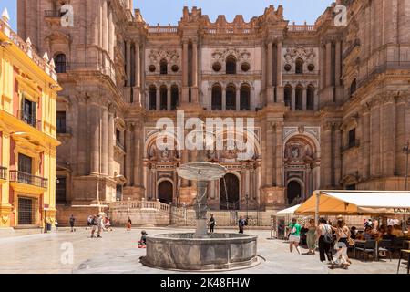 Fassade der Kathedrale von Malaga oder Santa Iglesia Catedral Basílica de la Encarnación, mit einem Brunnen und Touristen auf dem Stadtplatz im Vordergrund Stockfoto