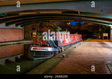 Kanalboote vertäuten im Morgengrauen unter einer Brücke auf dem Oxford-Kanal in Banbury. Castle Quay Waterfront. Banbury, Oxfordshire, England Stockfoto