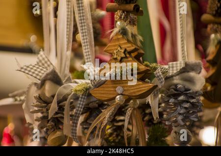 Advent-Basar-Stände mit Glas-, Holz-, Keramik-weihnachts-Souvenirs in einem Geschäft. Nahaufnahme von festlichen Baumdekorationen auf dem nächtlichen Wintermarkt auf der Straße Stockfoto