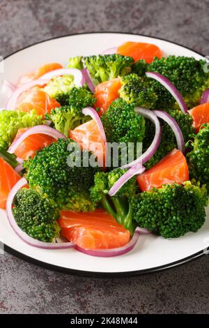 Brokkoli geräucherter Lachs roter Zwiebelsalat in Nahaufnahme auf einem Teller. Vertikal Stockfoto