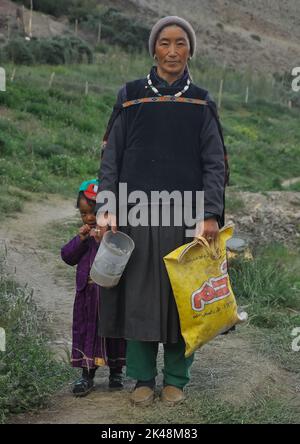 Padum, Zanskar, Kargil - District, Ladakh, Indien - 07 19 2022: Eine mitteljährige Ladakhi (Zanskar) Frau mit ihrer Tochter in ihrer traditionellen Kleidung, die im Freien auf die Kamera schaute Stockfoto