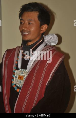 Nahaufnahme eines glücklichen Ladakhi Groom aus dem Zanskar-Tal, der seitwärts blickt und traditionelle Kleidung und Schmuck trägt Stockfoto