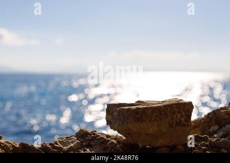 Leerraum mit schönem blauen Meereshintergrund für Montage Produkte Display. Stein vor einem Hintergrund von Strand, Wasser. Stockfoto