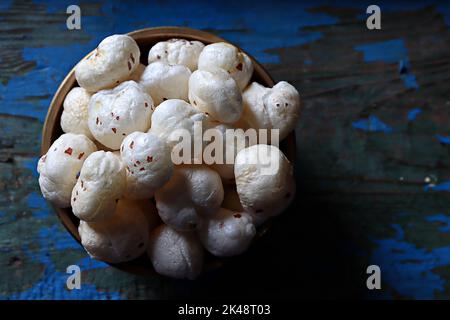 Nahaufnahme von gerösteten Fuchsnüssen/Makhana/Lotus-Samen in einer Messing-urli/Schüssel vor strukturiertem Hintergrund Stockfoto