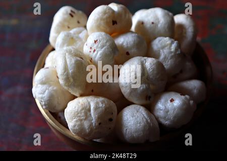 Nahaufnahme von gerösteten Fuchsnüssen/Makhana/Lotus-Samen in einer Messing-urli/Schüssel vor strukturiertem Hintergrund Stockfoto