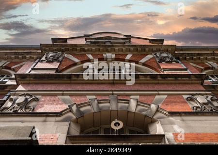 Verlassene alte viktorianische Arbeitshaus mit Sonnenuntergang und dramatischen Wolken. Altes rotes Ziegelgebäude. Stockfoto