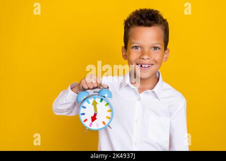 Foto einer fröhlichen Person strahlend Lächeln Arm halten zeigt Uhr isoliert auf gelbem Hintergrund Stockfoto