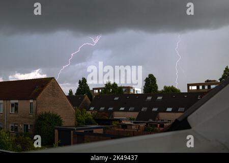 Dunkler Himmel mit Blitzeinschlägen über eine Stadt Stockfoto