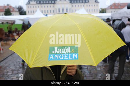 Wermsdorf, Deutschland. 01. Oktober 2022. Vor dem Schloss Wermsdorf trägt ein Besucher einen Regenschirm mit dem Logo der Messe „Jagd & Angeln“. Dort findet vom 01. Bis 03.10.2022 die größte Messe Ostdeutschlands zu den Themen Jagd, Fischerei und Outdoor statt. Die Show findet zum ersten Mal in diesem historischen Ambiente statt, zuvor fand sie in Markkleeberg bei Leipzig statt. Quelle: Sebastian Willnow/dpa/ZB/dpa/Alamy Live News Stockfoto