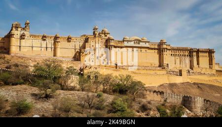 Amber Fort beleuchtet durch warmes Licht der aufgehenden Sonne und reflektiert im See. Berühmtes Wahrzeichen von Rajasthan, Indien Stockfoto