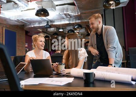 Fröhliches Architekturteam, das in Großraumbüros arbeitet Stockfoto
