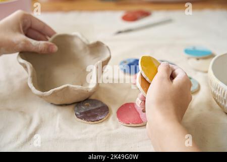 Die Kunsthandwerkerin hält Teller und Farbproben in den Händen Stockfoto