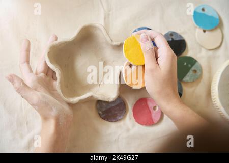 Frau hält handgefertigte Teller und Farbmuster in ihren Handflächen Stockfoto