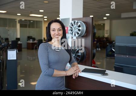 Charmante weibliche Consultant auf dem Hintergrund eines Autohauses Interieur Stockfoto
