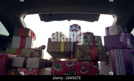 weihnachtsmann liefert Geschenke. Geschenke vom weihnachtsmann. Lieferservice. Deliveryman lädt Boxen. Geschenk-Boxen im Auto. Schön verpackte Pakete. Blick aus dem Inneren des Autos. Spende, Wohltätigkeit oder Lieferkonzept. Hochwertige Fotos Stockfoto