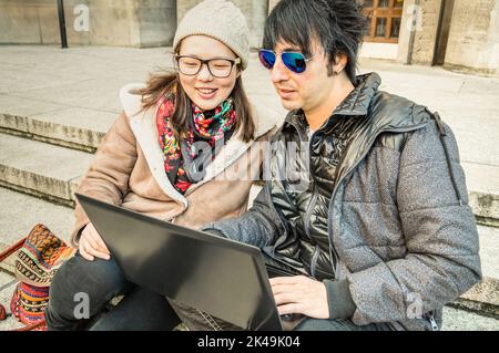 Multirassisches Paar, das Spaß mit dem Laptop hat - modernes Konzept der Verbindung mit Computertechnologie - städtischer Lebensstil und Beziehung zum Alltag - Stockfoto