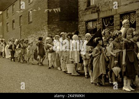 Aufgeregte Kinder in selbstgemachten Kostüen lachen und plaudern, während sie wahrscheinlich in der Wakefield Road darauf warten, in der Prozession, die am 6. Mai 1935 zur Feier des Silberjubiläums von König George V in Denby Dale in West Yorkshire, England, stattfand, weiter zu gehen. Stockfoto