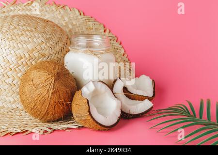 Gerissenes Coco und Kokosmilch im Glas auf hellem rosafarbenem Hintergrund Stockfoto