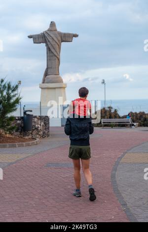 Eine junge Frau mit ihrem Sohn auf dem Rücken am Aussichtspunkt Cristo Rei in Funchal, Madeira Stockfoto