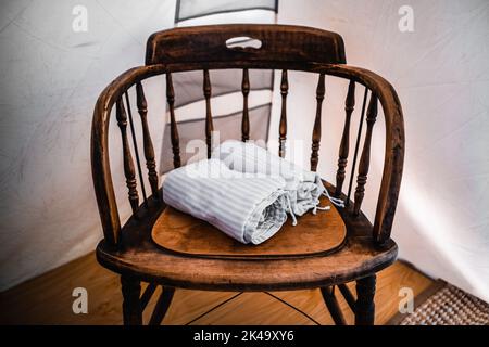 Gefaltete, saubere Kissenbezüge, aufgerollt auf einem alten Holzstuhl im Campingzelt Stockfoto