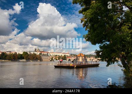 Die Gedenkglocke #9801 auf einem Ponton in der Moldau bei Smetanovo nábřeží. Prag. Prager Burg und Karlsbrücke im Hintergrund. Stockfoto