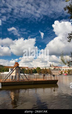 Die Gedenkglocke #9801 auf einem Ponton in der Moldau bei Smetanovo nábřeží. Prag. Prager Burg und Karlsbrücke im Hintergrund. Stockfoto