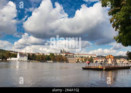 Die Gedenkglocke #9801 auf einem Ponton in der Moldau bei Smetanovo nábřeží. Prag. Prager Burg und Karlsbrücke im Hintergrund. Stockfoto