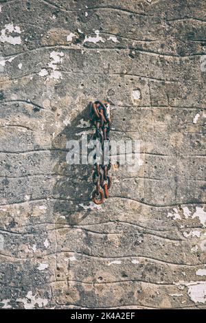 Rostige alte Kette, die an einer Wand hängt Stockfoto