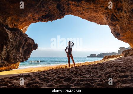 Ein attraktives kaukasisches Weibchen in der natürlichen Höhle an der Algarve in Praia da Coelha, Albufeira Stockfoto