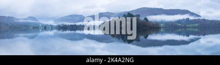 Rydal fiel und die Küste von Grasmere spiegeln sich in den spiegelruhigen Gewässern des Sees an einem bewölkten Morgen mit Nebel, der zwischen den Fjells driftet. Stockfoto