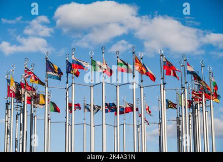 Flaggen der Länder der Welt auf Fahnenmasten am blauen Himmel an einem sonnigen Tag Stockfoto